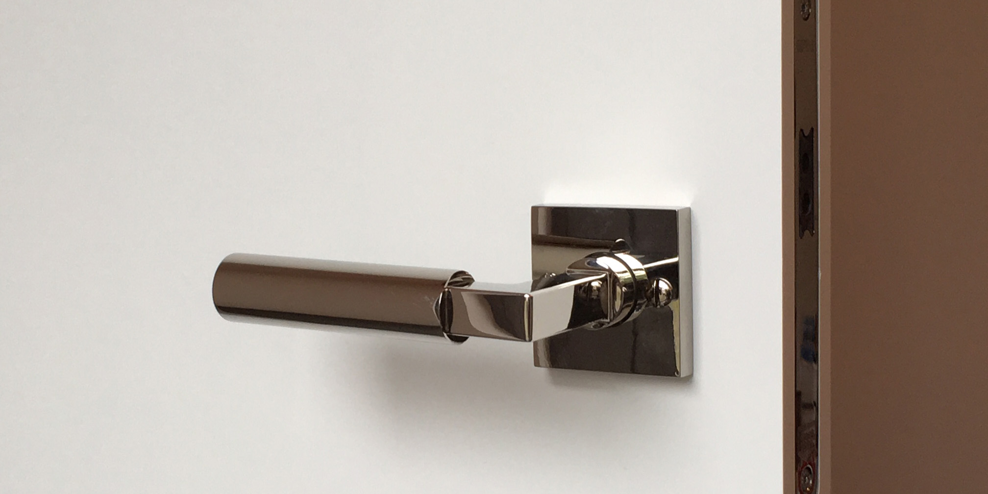 Drückerbeschlag Bauhaus mit quadratische Rosette in nickel,poliert montiert auf einem weißen Türblatt